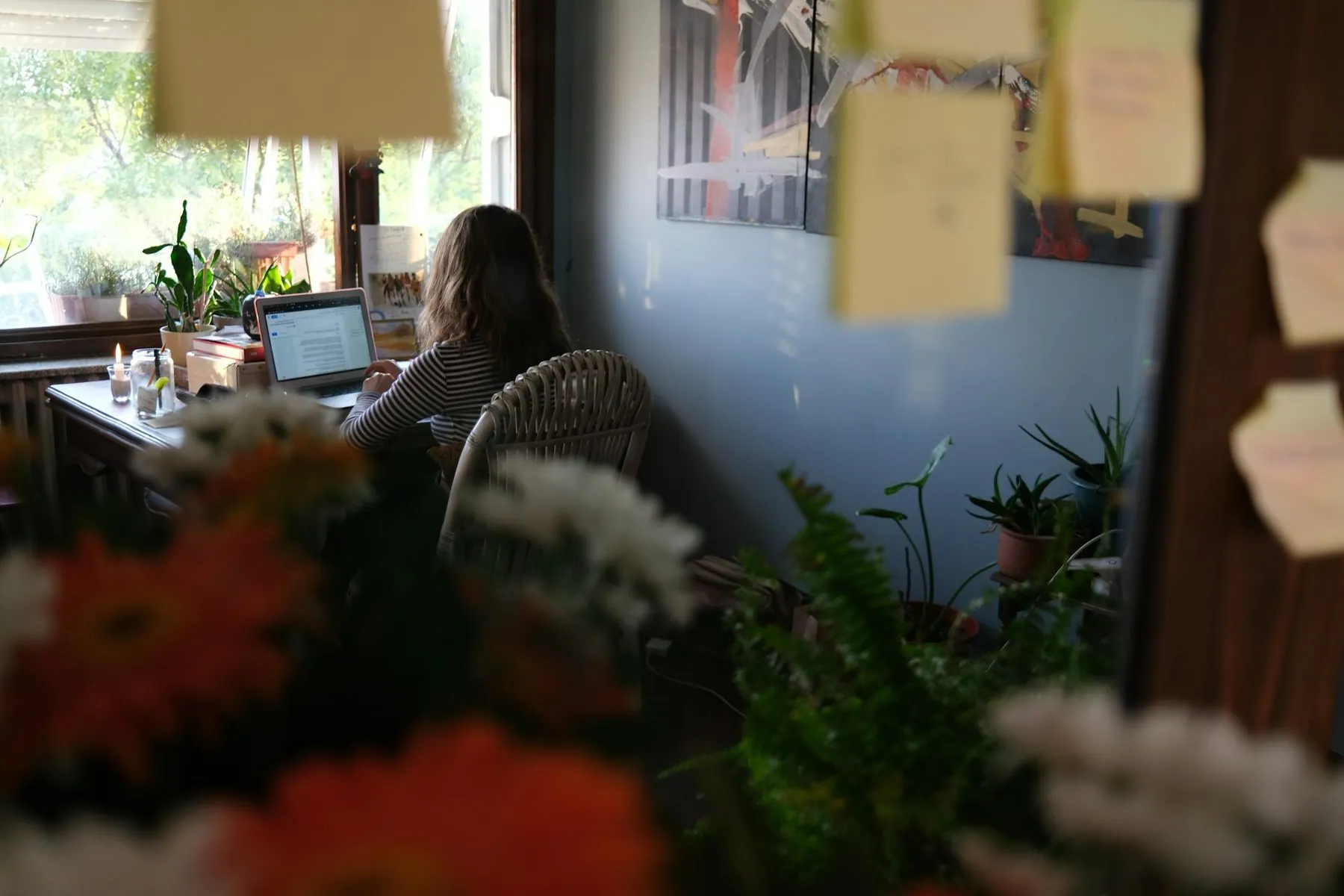 Woman working on laptop at a desk with plants
